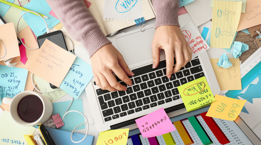Overwhelmed person searching through multiple SEO dashboards and her desk is very messy with to do lists